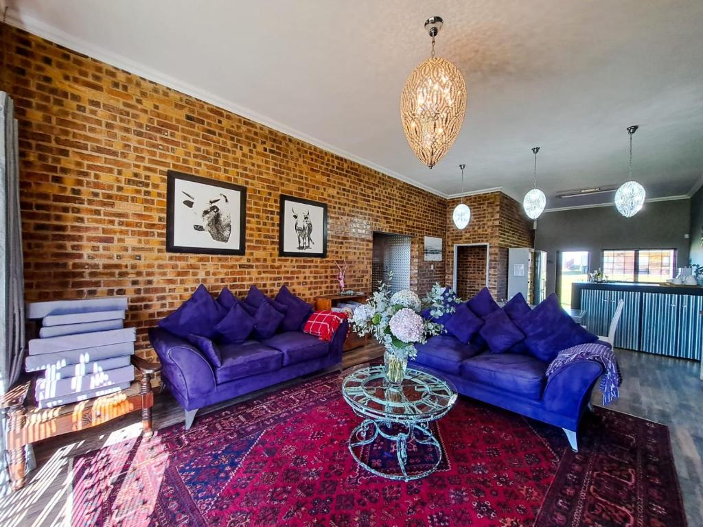una sala de estar con sofás morados y una pared de ladrillo en Dullstroom Manor Game & Trout Lodge, en Dullstroom