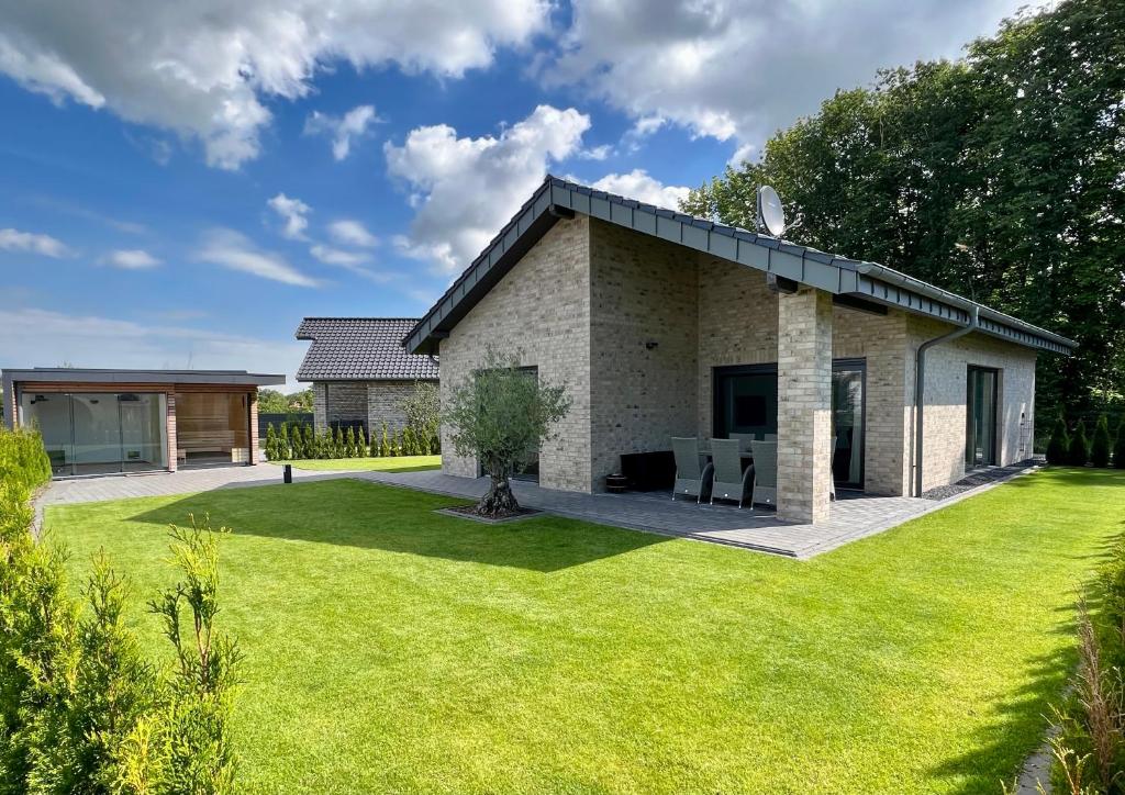 ein Haus mit einem großen Hof in der Unterkunft Schönes Ferienhaus mit Sauna am Harkebrügger See in der Nähe von Oldenburg in Barßel