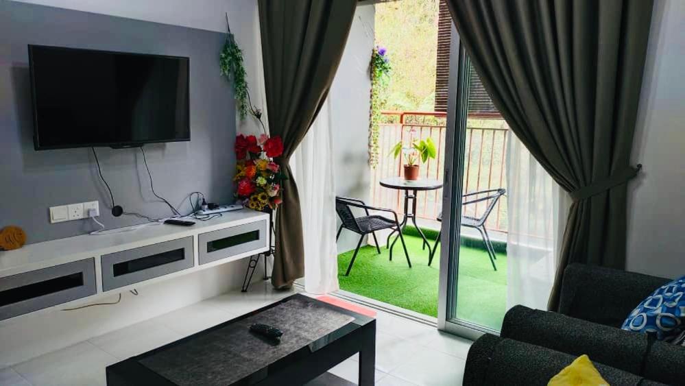 a living room with a television and a balcony with a table at SA @ Cameron Emerald Avenue in Brinchang
