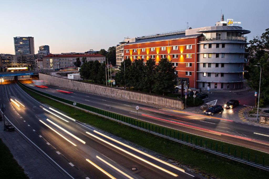 uma movimentada rua da cidade com edifícios e carros à noite em Art City Inn em Vilnius