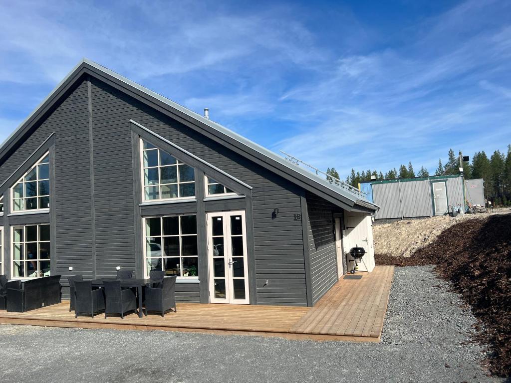 a gray house with a wooden deck with black chairs at New cabin in fabulous Idre activity area in Idre