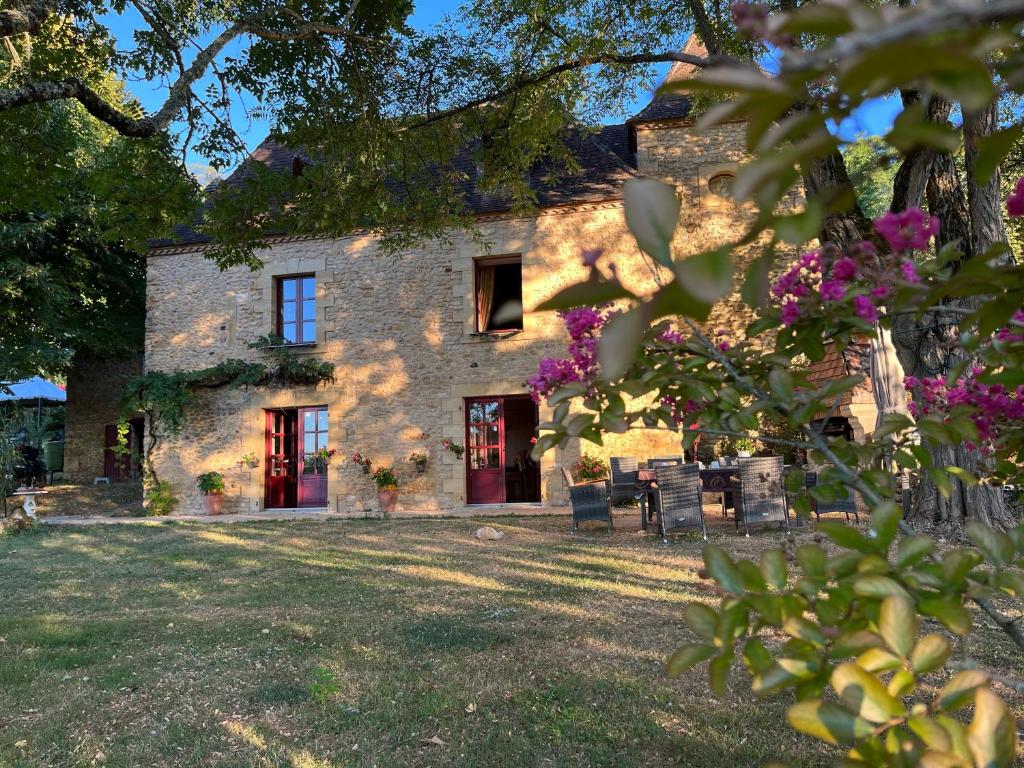 a stone house with purple flowers in front of it at roquebrune in Saint-Alvère