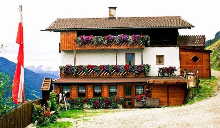 une maison avec des boîtes de fleurs sur son côté dans l'établissement Ferienwohnung Oberpursteinhof, à Campo Tures