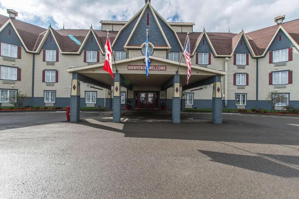 un grand bâtiment avec drapeaux devant lui dans l'établissement Quality Inn, à Rivière-du-Loup