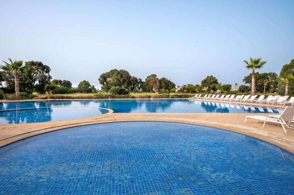 Radisson Blu Resort, Saidia Garden في السعيدية: مسبح كبير مع كراسي وماء ازرق