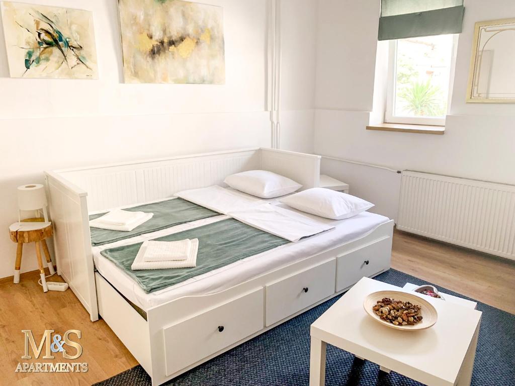 uma cama branca num quarto com uma mesa em Matija Apartment em Novi Sad