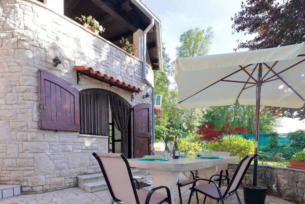 een tafel en stoelen en een parasol op een patio bij Apartman Villa Marina in Rakalj