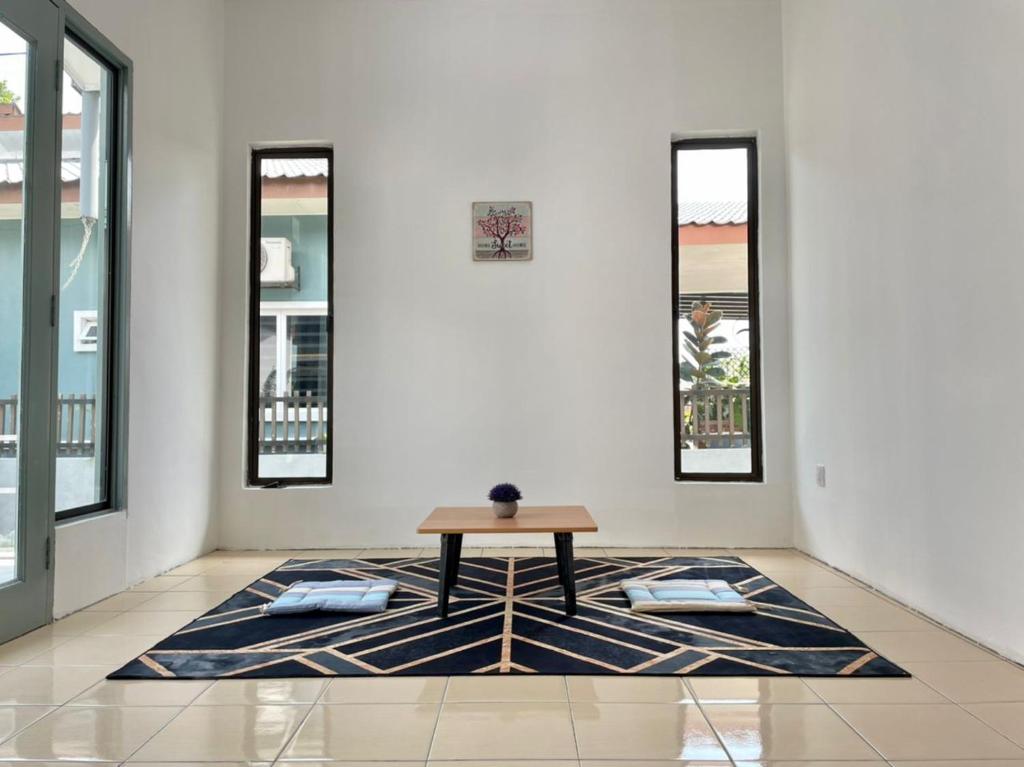 a table on a rug in a room with windows at Inderaloka Villa 23B Free Parking in Shah Alam