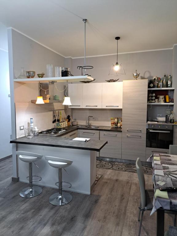 une cuisine avec des placards blancs et un îlot avec des tabourets de bar dans l'établissement Welcome home, à Terni