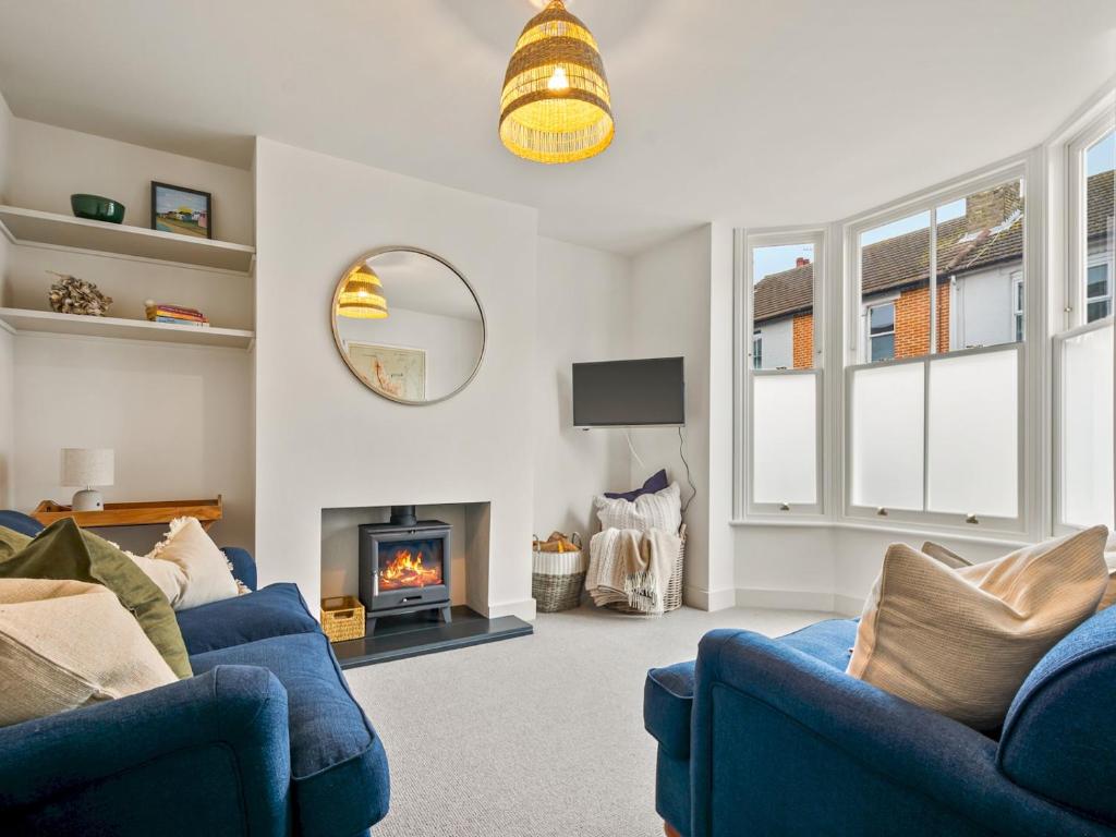 a living room with two blue couches and a fireplace at Limewood Newly Renovated High End Home by the Sea in Whitstable