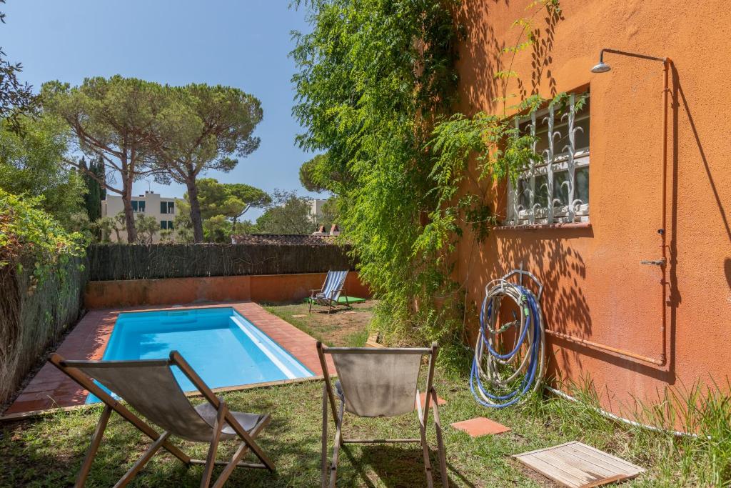 um quintal com uma piscina e duas cadeiras e um edifício em Illes Medes a el Golfet em Palafrugell