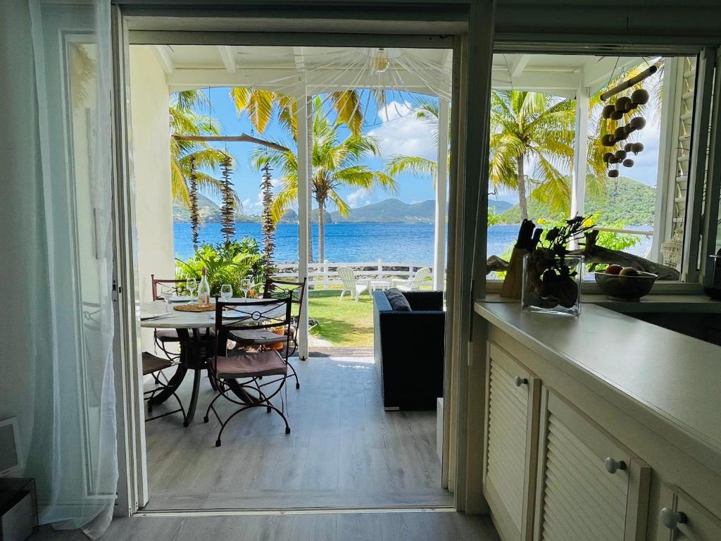 a kitchen with a table and a view of the ocean at Blue Lagoon, cottage les pieds dans l eau in Terre-de-Haut
