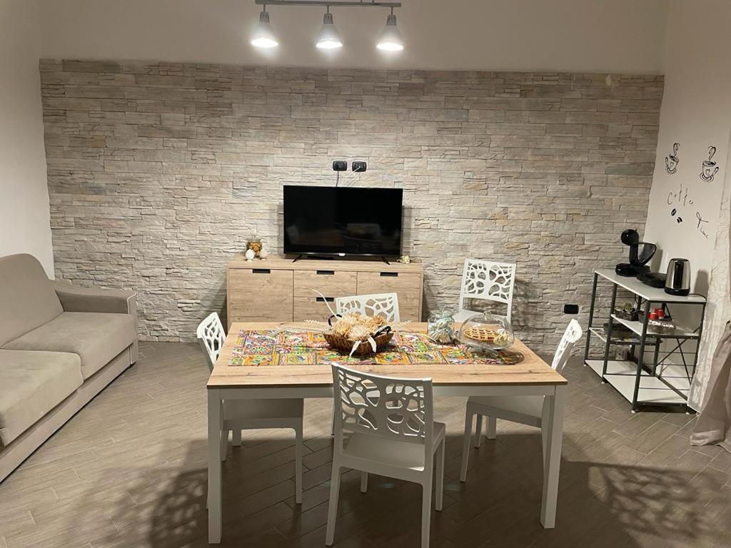 ein Wohnzimmer mit einem Tisch mit Stühlen und einem TV in der Unterkunft La Pietra di Giada in Syrakus