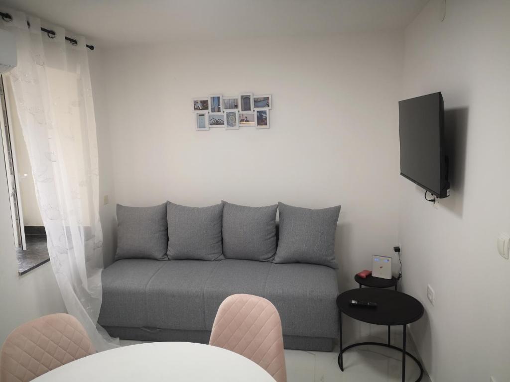 ein Wohnzimmer mit einem Sofa und einem TV in der Unterkunft Apartman Hobit in Opatija