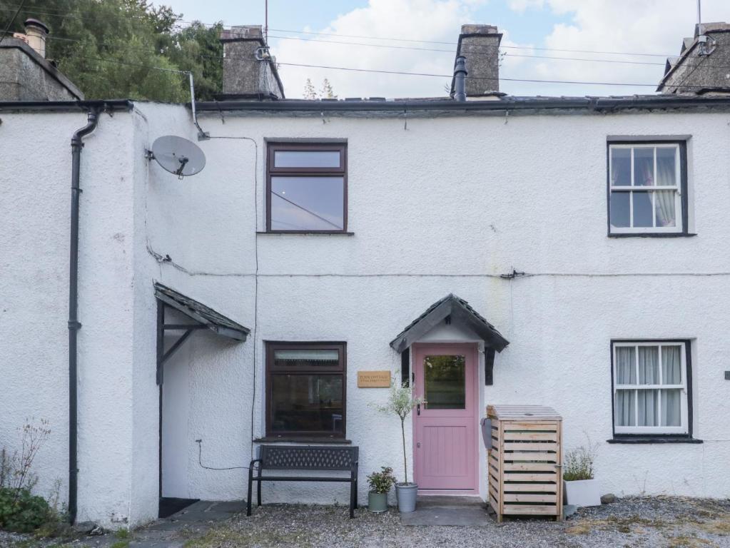 a white house with a pink door at Turn Cottage in Ulverston