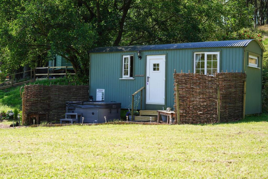ein winziges Haus in einem Garten mit einem Zaun in der Unterkunft The Laburnum Retreat Shepherd Hut private hot Tub in Upper Hulme