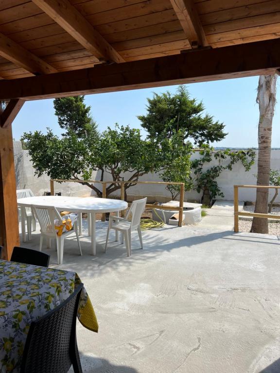 patio z białym stołem, krzesłami i drzewami w obiekcie Appartamento - Isola di Mothia w mieście Marsala