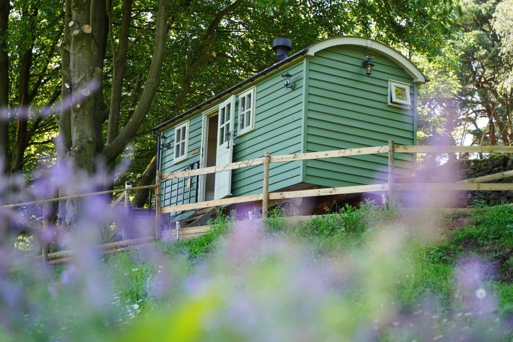 a green tiny house sitting in the woods at Lavender Retreat with Private Hot Tub in Upper Hulme
