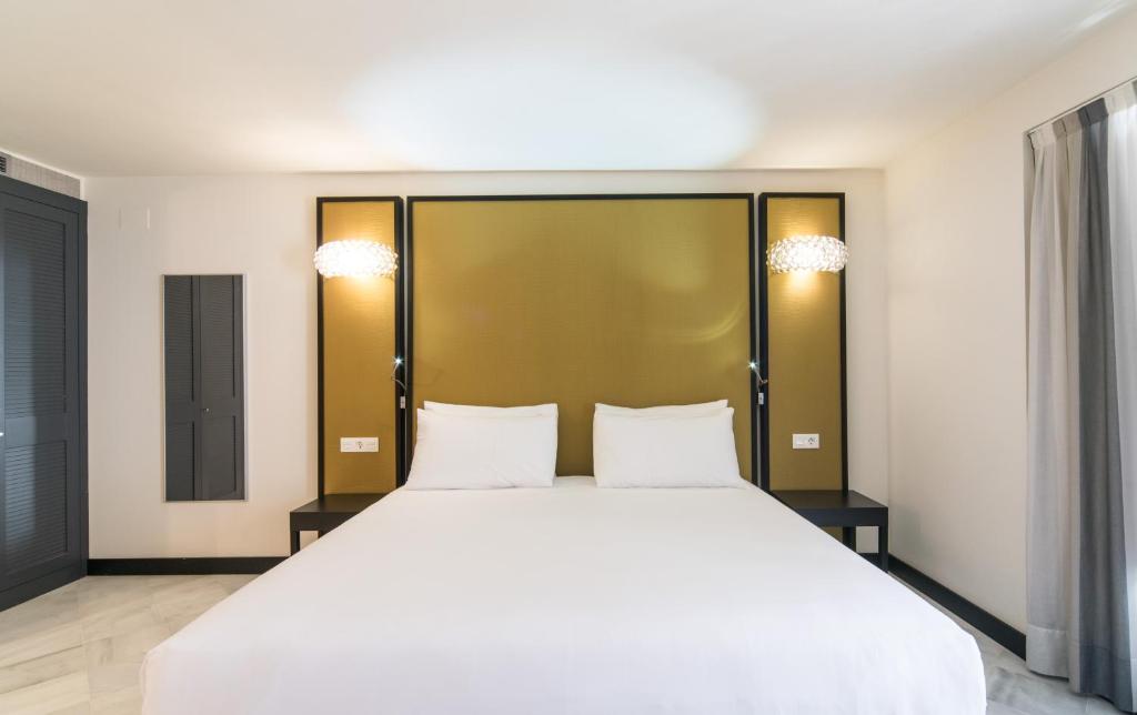 a bedroom with a large white bed with two pillows at Hotel Palacio Marqués de Arizón in Sanlúcar de Barrameda