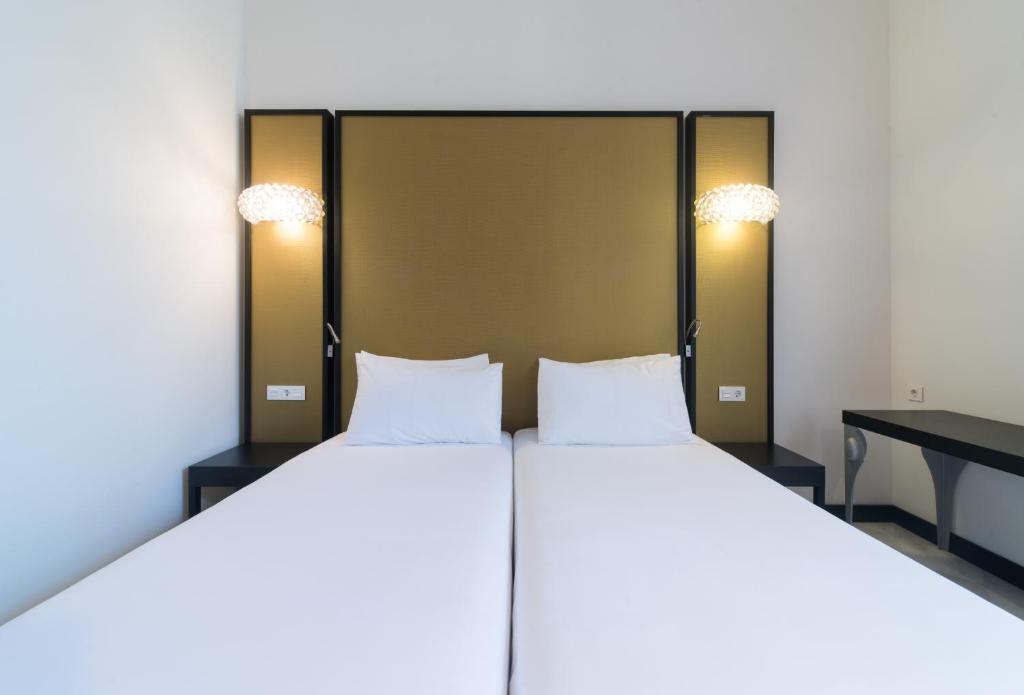 a bedroom with two large beds and a table at Hotel Palacio Marqués de Arizón in Sanlúcar de Barrameda