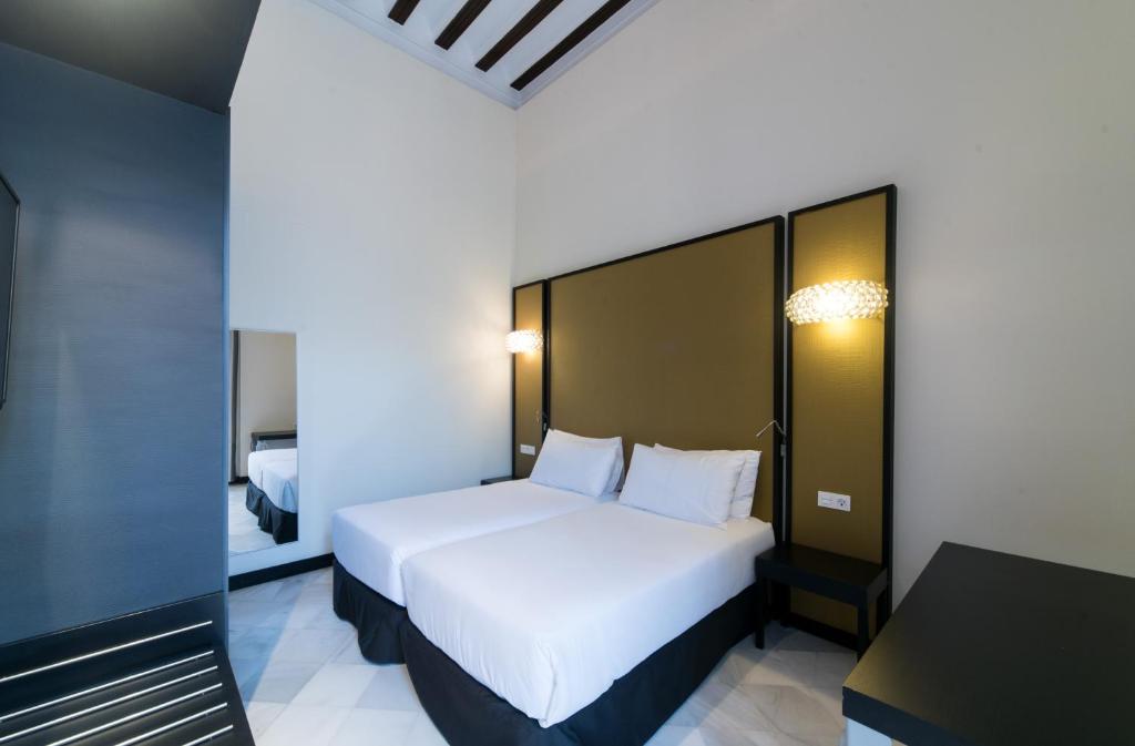a bedroom with a large white bed and a desk at Hotel Palacio Marqués de Arizón in Sanlúcar de Barrameda