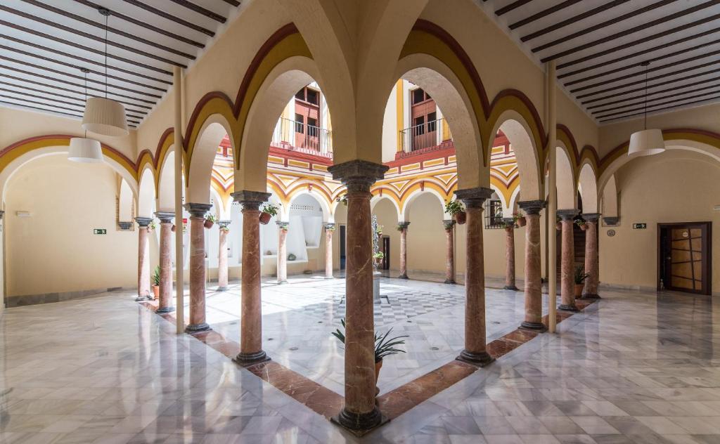 an arcade with columns and arches in a building at Hotel Palacio Marqués de Arizón in Sanlúcar de Barrameda