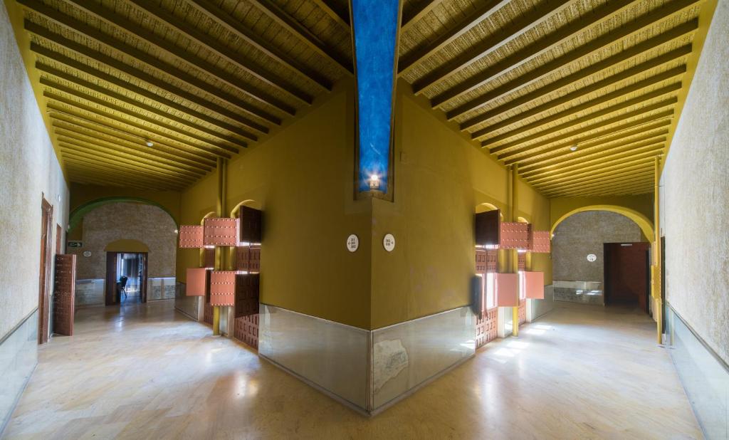 a large room with yellow walls and a wooden ceiling at Hotel Palacio Marqués de Arizón in Sanlúcar de Barrameda