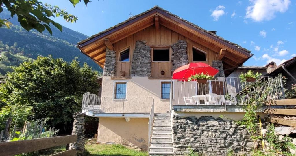 uma casa com uma varanda com um guarda-chuva vermelho em Valle D'Aosta a 360° - Ideal for smart working em Aymavilles