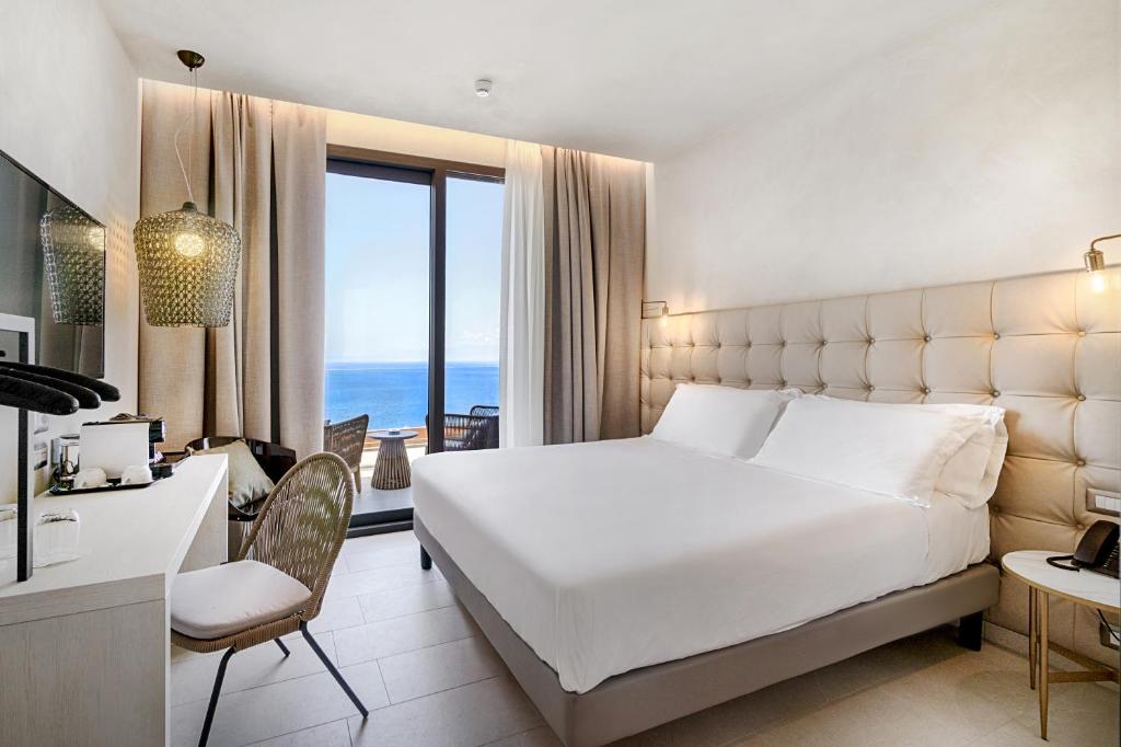 una camera con un grande letto bianco e una scrivania di Villa Fiorita Boutique Hotel a Taormina