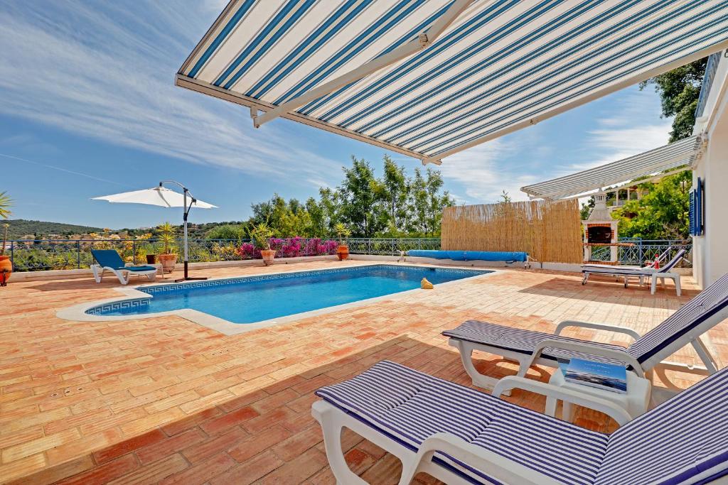 um quintal com uma piscina e um pátio com mesas e cadeiras em Casa dos Sonhos by Portucasa em São Brás de Alportel