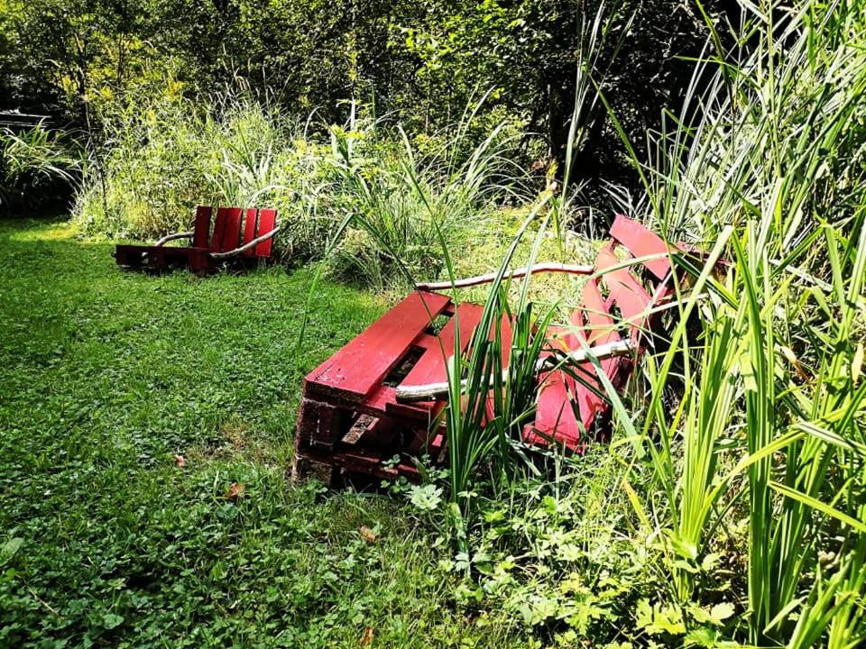 a red bench sitting in the grass in a field at Lodge bien être et nature in Soultzeren