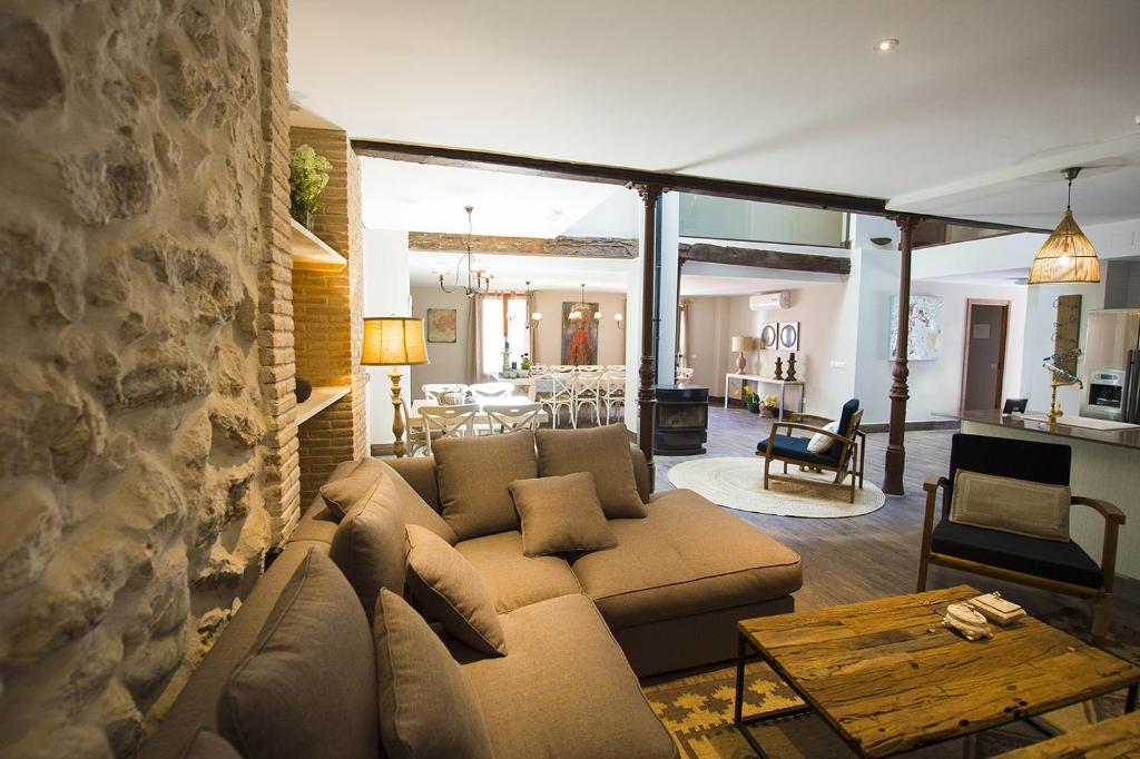 ein Wohnzimmer mit einer Couch und einer Steinwand in der Unterkunft Casa Rural Valle de la Laguna in Valdelaguna