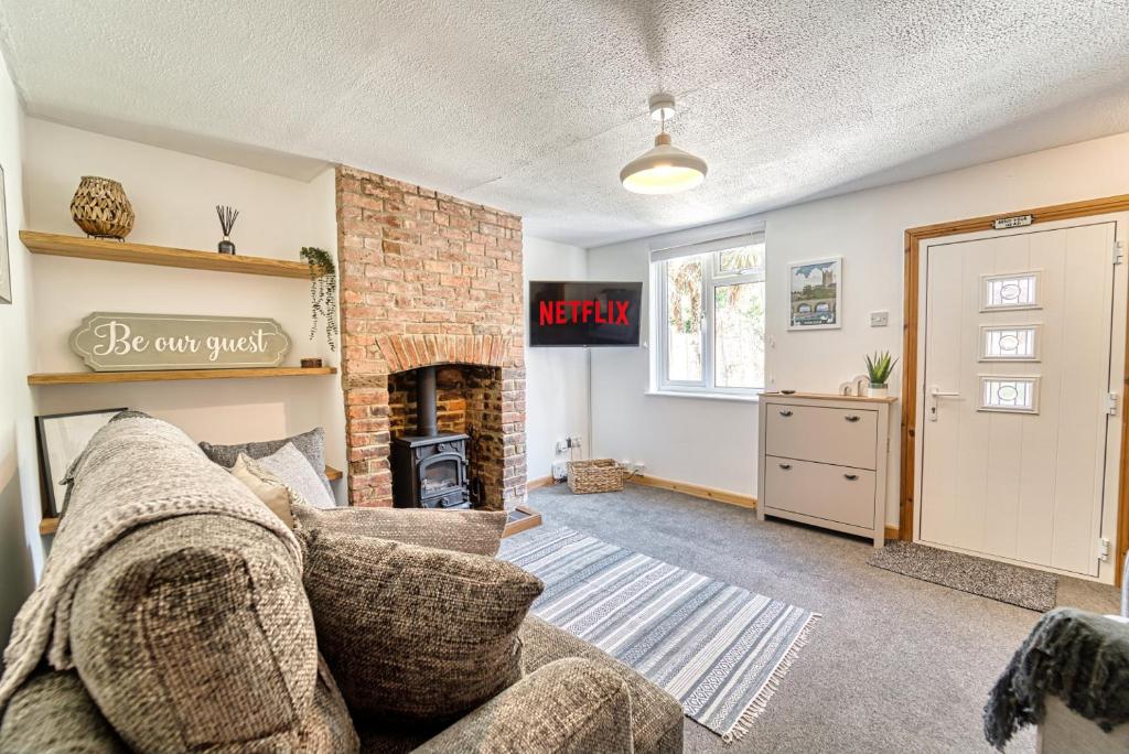 een woonkamer met een bank en een open haard bij Guest Homes - London Road Cottage in Worcester