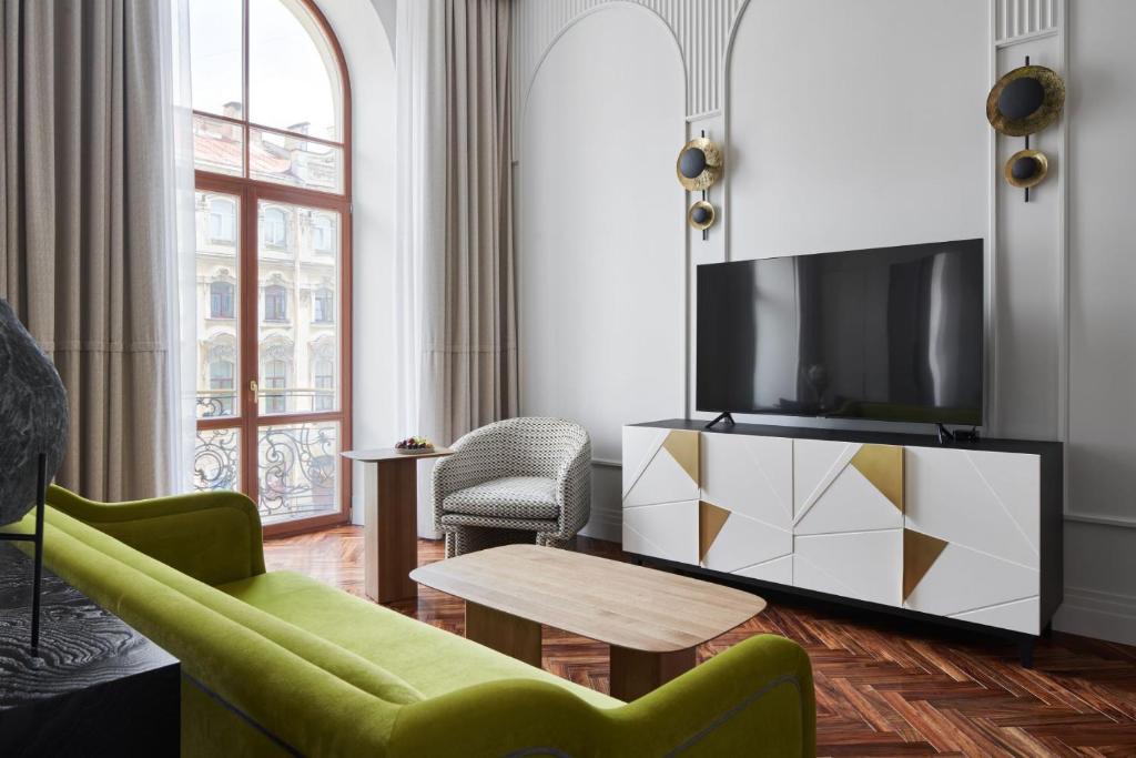 ein Wohnzimmer mit einem TV, einem Sofa und einem Tisch in der Unterkunft Helvetia Hotel in Sankt Petersburg