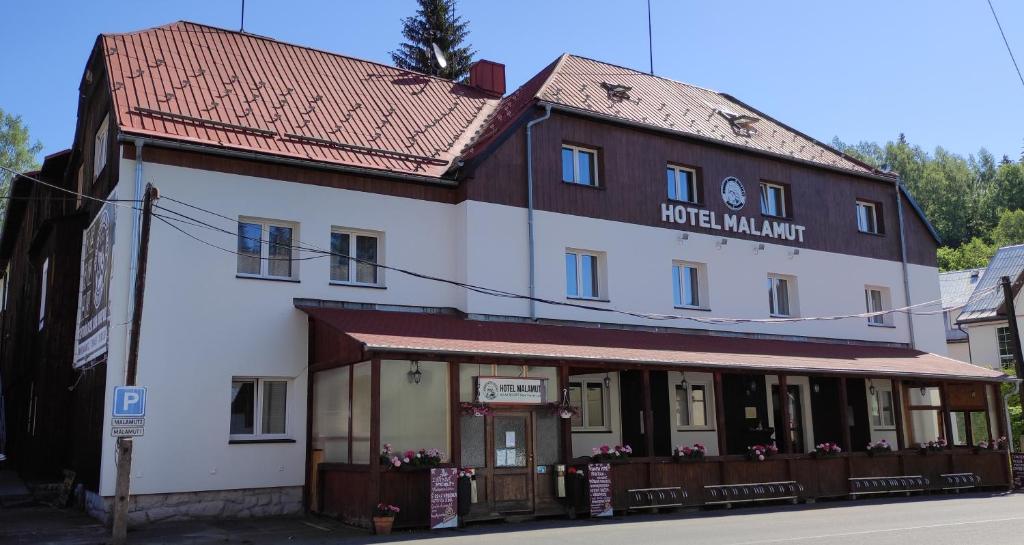 ein großes weißes Gebäude mit rotem Dach in der Unterkunft Hotel Malamut in Nové Hamry