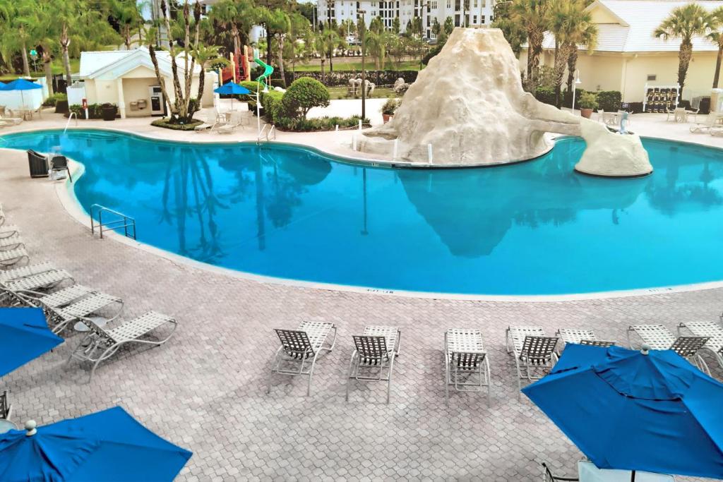 a large swimming pool with chairs and umbrellas at Cypress Pointe Resort in Orlando