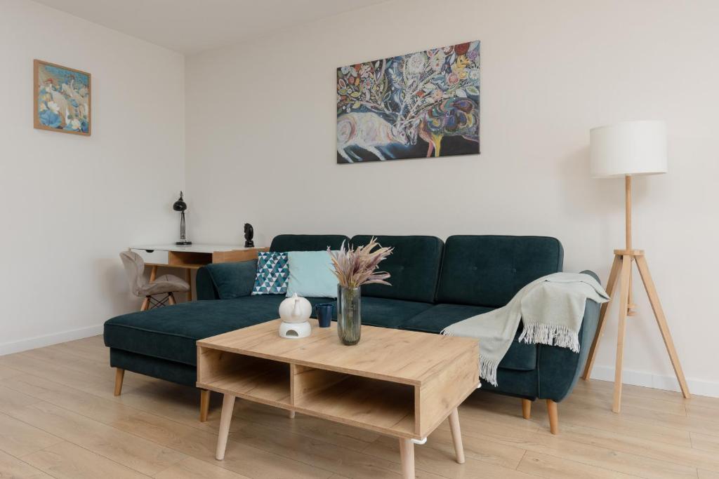 ein Wohnzimmer mit einem grünen Sofa und einem Tisch in der Unterkunft Chłodna Apartment European Square Warsaw by Renters in Warschau