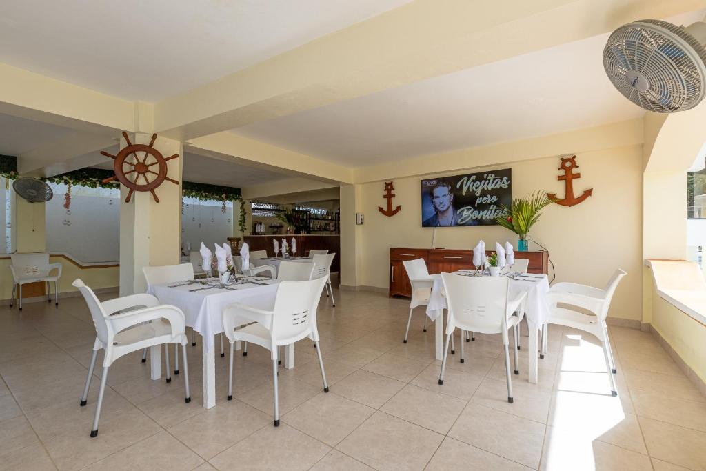 una sala da pranzo con tavoli bianchi e sedie bianche di Hotel Turístico Marian a Las Terrenas