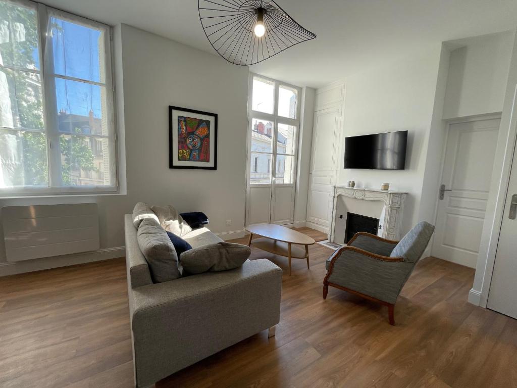 een woonkamer met een bank en een stoel bij Appartement Le Corneille centre ville climatisé in Saumur