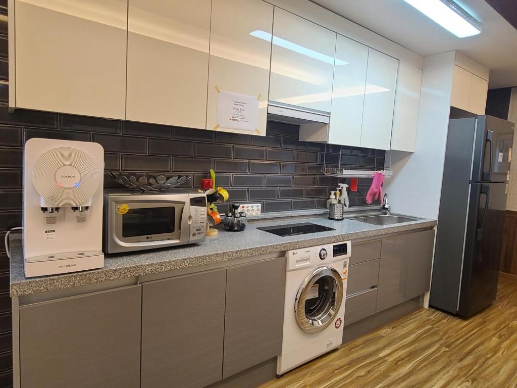 a kitchen with a washing machine and a microwave at TreehouseUnseo GuestHouse in Incheon