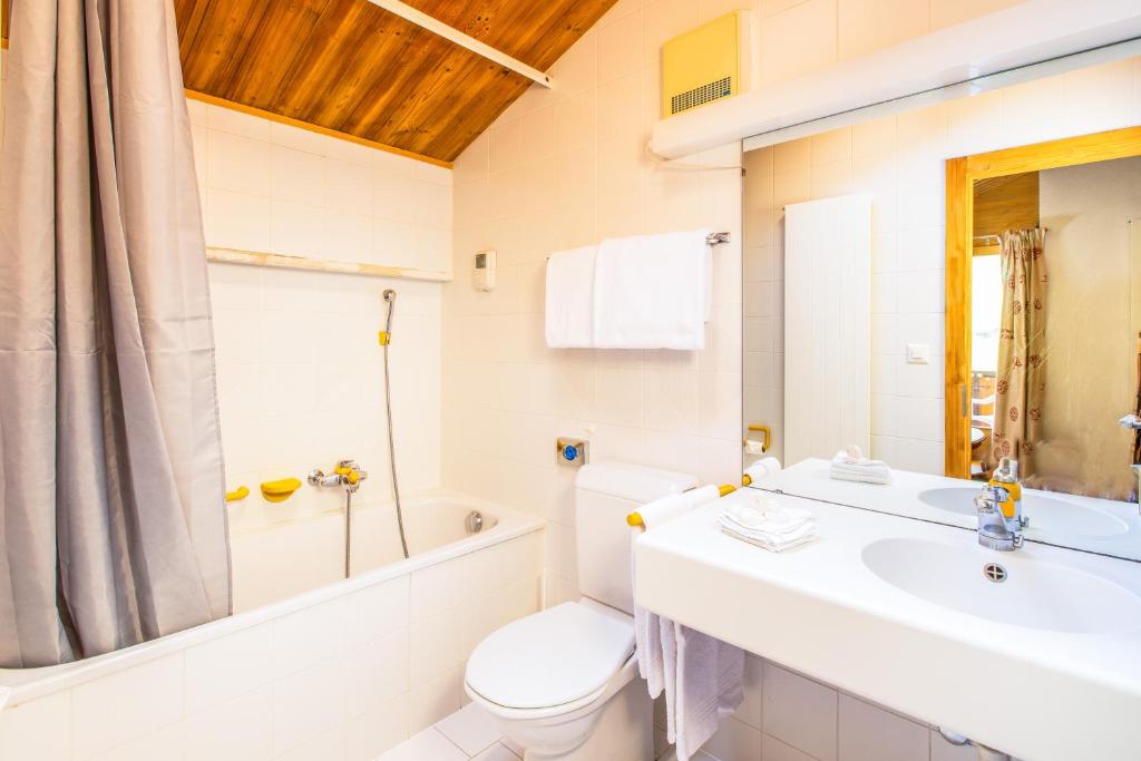 a white bathroom with a sink and a toilet at Hôtel Magrappé in Veysonnaz