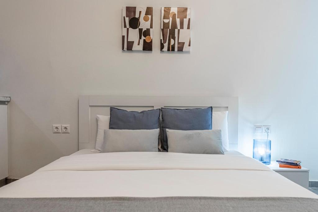 um quarto com uma grande cama branca com almofadas azuis em Phaedrus Living: City Center Executive Flat Stadiou em Atenas