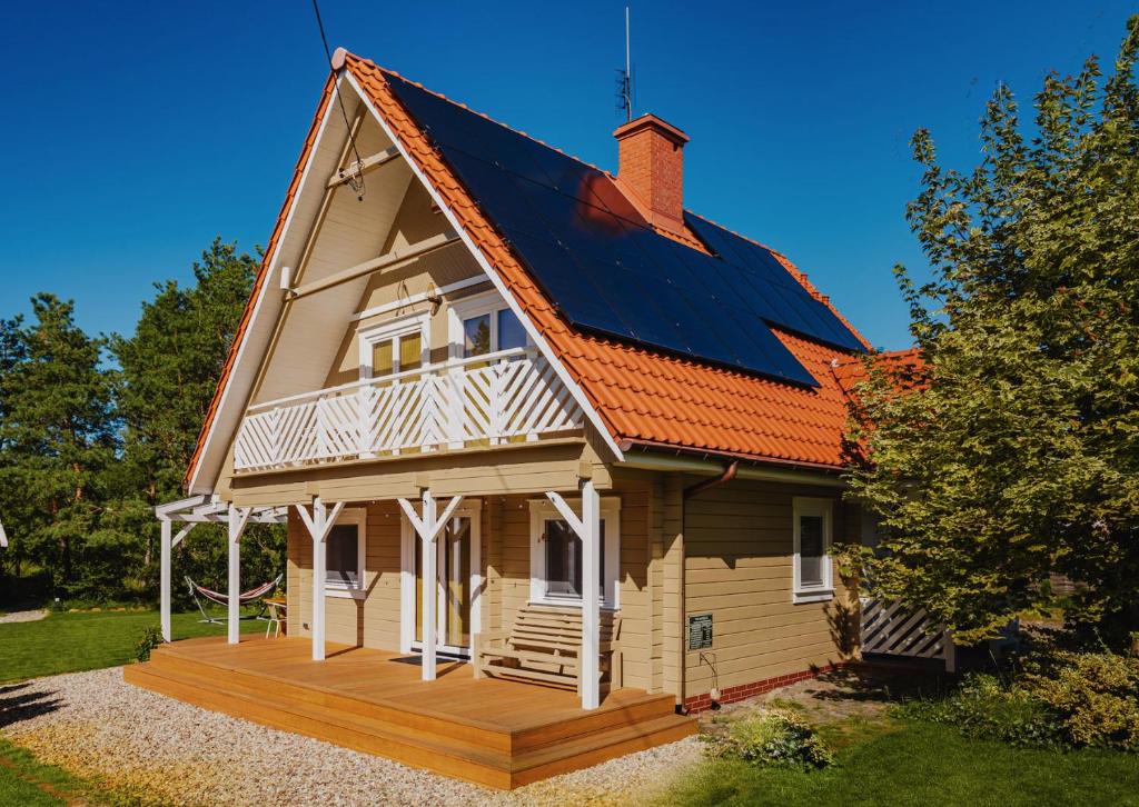 una casa con techo solar en una terraza de madera en Dom pod Klonem, en Jantar