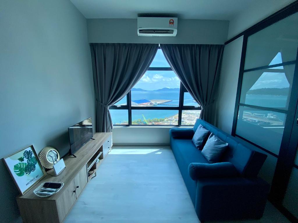 een woonkamer met een blauwe bank en een groot raam bij KK City Jesselton Quay near Suria Mall by JR Homestay in Kota Kinabalu