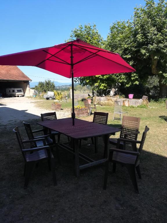 - une table de pique-nique avec un parasol et des chaises rouges dans l'établissement Ferme les poneys de la Durme, à Chélieu
