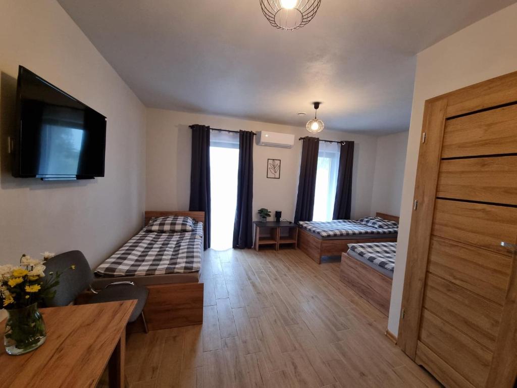 uma sala de estar com duas camas e uma televisão em Pokoje pod Wietrznią em Kielce