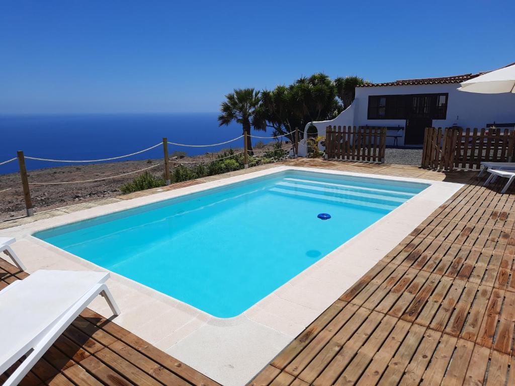 a swimming pool with a wooden deck and blue water at Casa Los Llanos in Playa de Santiago