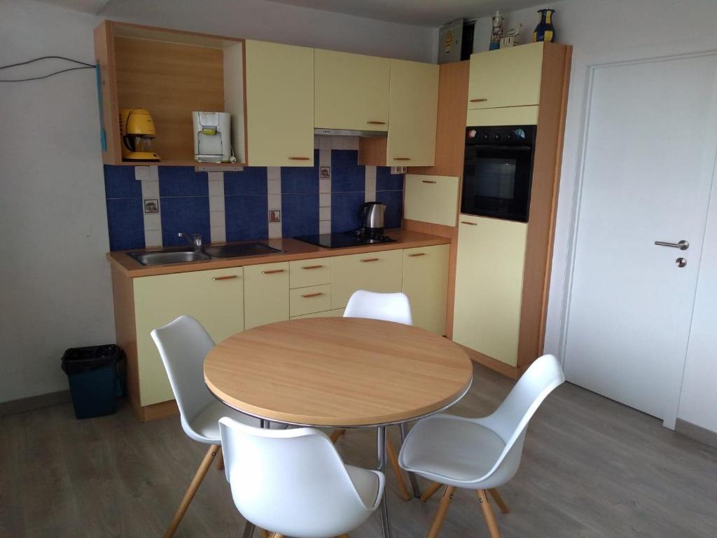 a kitchen with a wooden table and white chairs at Joy Lotus 105 in De Haan