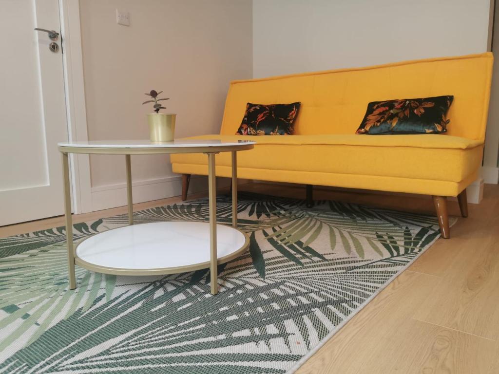 a living room with a yellow couch and a table at 360 Town Stay Apartments & Studios in Dungarvan