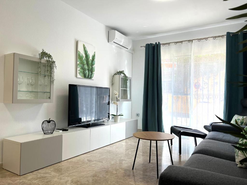 uma sala de estar com uma televisão de ecrã plano num armário branco em Apartamento Ninfa - Wifi, Piscina, A/C, Lavadora, silla de ruedas bienvenidas em Fuengirola